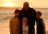 image of Boppa with James, Will and Charlie at the beach after a storm