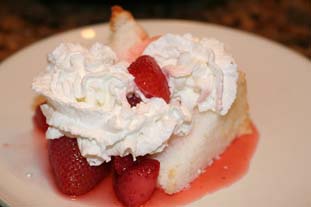 Slice of angel food cake topped with whipped cream and strawberries
