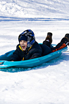 boy screaming as he sleds down a hill