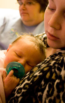 new mom holding baby on first night home with grandma watching