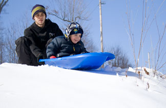 boy waiting on sled to be pushed by his brother