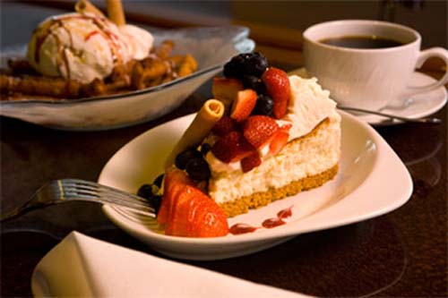 photo of cheesecake with berries on top of white plate.