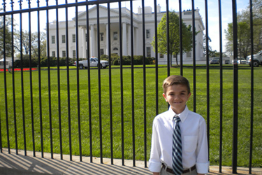 A kid poses for a photo outside of the White House