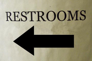 Restroom sign with big black arrow pointing to the left