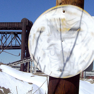Round sign obscured with white paint and graffiti