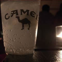 Glass with Camel logo on table at bar