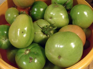 Bowl filled with many green tomatoes, all sizes and colors